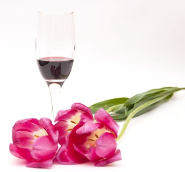 Glass of red wine with bouquet of spring colours on white background