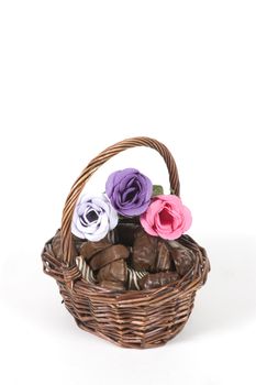 dark brown basket filled with chocolate and roses isolated on white