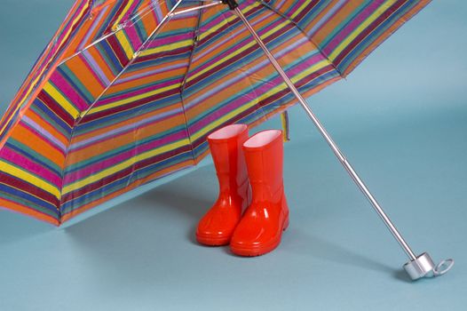 Red children rain boots and a colorful umbrella