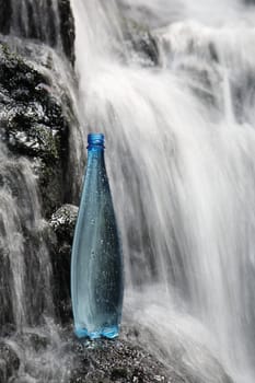 A blue bottle of fresh mineral water in waterfalls