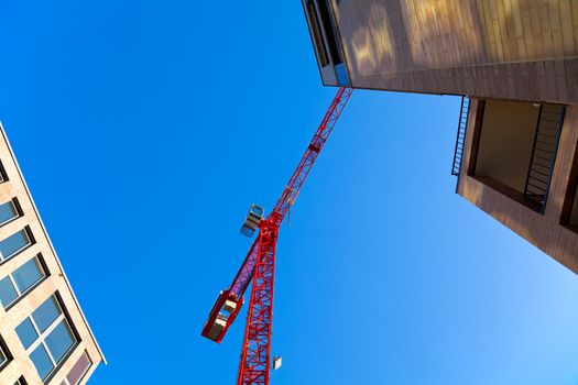 Contruction site with a red crane and two buildings. Copyspace.
