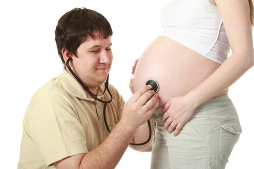 Happy expectant father listening to his wife's pregnant belly with a stethoscope 