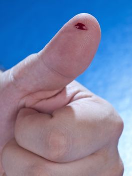 Close up on a drop of real blood on a human thumb.