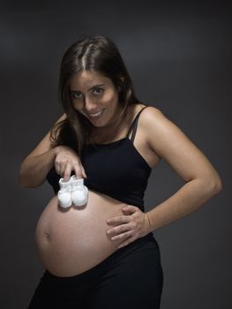 Pregnant woman holding a pair of white baby booties.