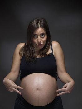 A mother to be shows her stomach with two fingers as if she was waiting twins.