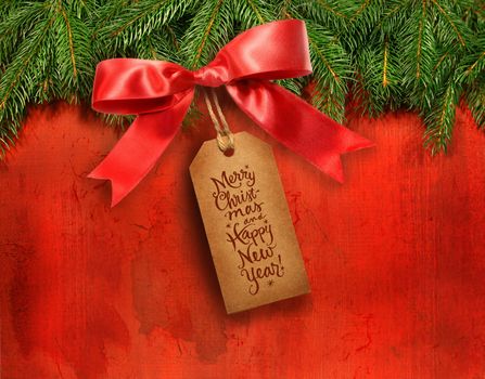 Pine branches with gift tag on grungy red background