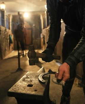 farrier prepares to attach horseshoe to hoof