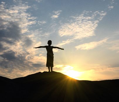 young man go up in sand desert in sundown silhouette