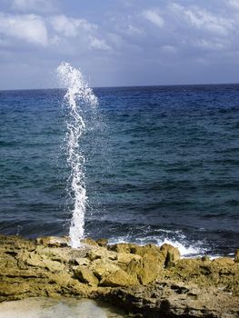 Water being shot out of a hole by crashing waves