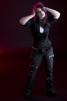 Goth girl with pink hair and body piercing holding her black and pink hair