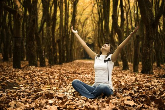 Happy woman seated on the ground with arms open