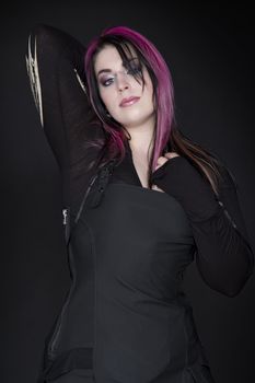 teenage girl wearing goth inspired clothes with pink and black hair in a pin up pose
