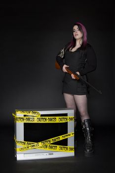 women holding rifle standing beside a television with yellow danger tap on it