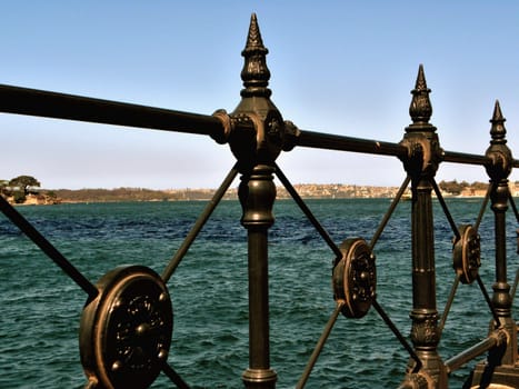Photo presents decorative railing with ocean in background.