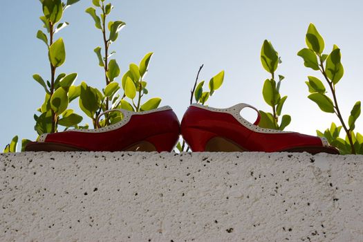 red high heels on a white wall with nature background