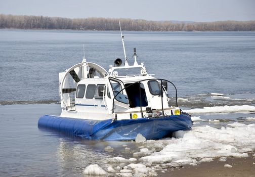 Hovercraft is on the icy shore waiting for passengers to carry across a river.