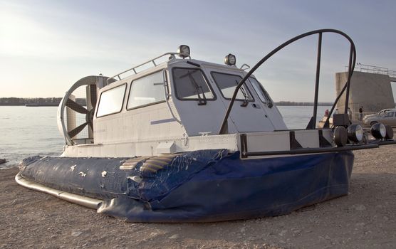 Hovercraft is on the beach waiting for passengers to carry across a river.