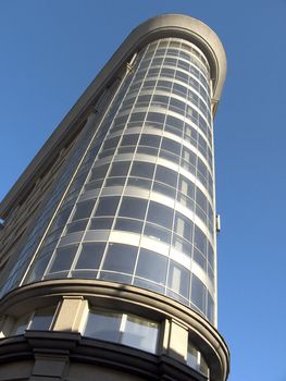 The glass facade of a skyscraper with the curtain walls on a background of blue sky.