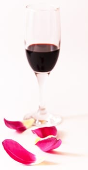 Glass of red wine with petals of spring flower