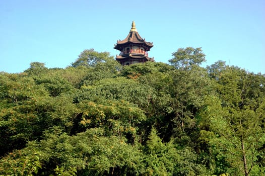 Traditional, wooden tower surrounded by green trees in Chinese park. Shaoxing city, Zhejiang province, China.