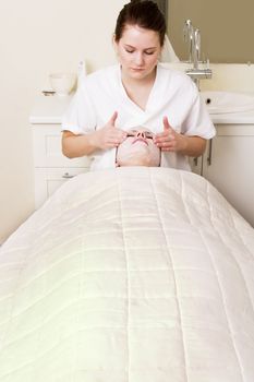 Lotion being massaged in during a facial at a beauty spa.