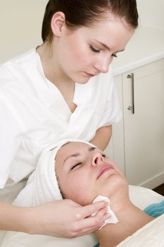 Lotion being wiped off during a facial at a beauty spa.