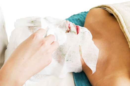 Lotion being applied to the face during a facial mask at a beauty spa.