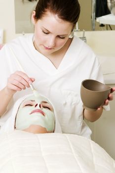 A detail image of a green apple mask being applied at a beauty spa.