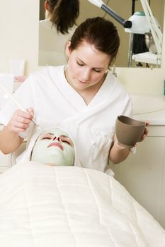 A detail image of a green apple mask being applied at a beauty spa.