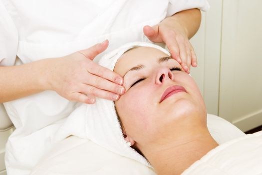 A woman receiving a facial massage at a beauty spa.