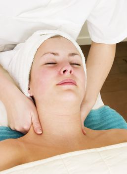 A woman receiving a facial and shoulder massage at a beauty spa.