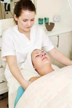A woman at a day spa, recieving a facial and should massage
