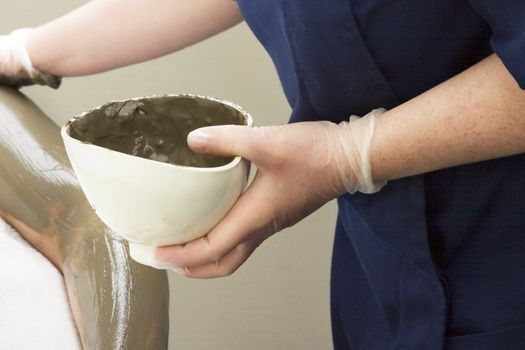 A detail image of a sea mud full body wrap at a luxury spa being applied to the arm.