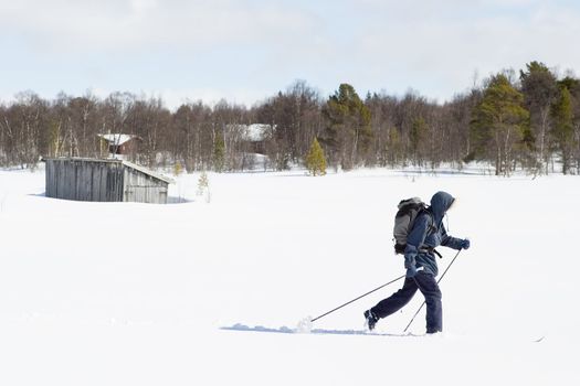 A skier with a large backpack on a wintery snow filled landscape.