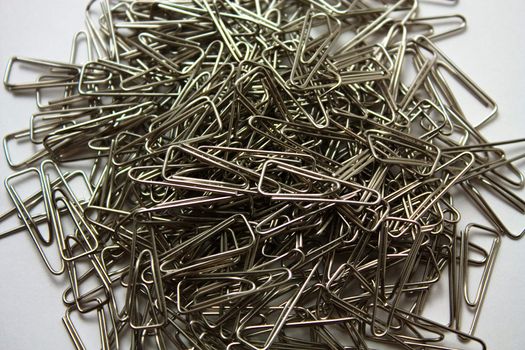 A lot of metallic paperclips on a white background