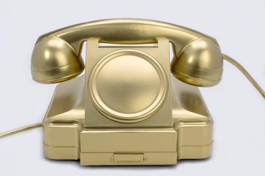 The telephone of gold colour on a white background.
