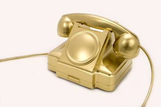 The telephone of gold colour on a white background.
