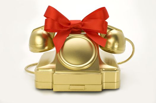 The telephone of gold colour with a red tape on a white background.