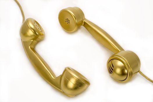 Two telephones of gold colour on a white background.