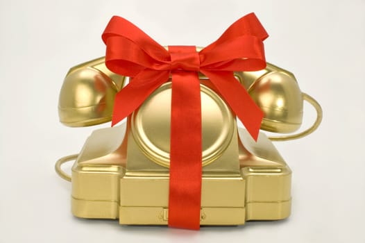 The telephone of gold colour with a red tape on a white background.