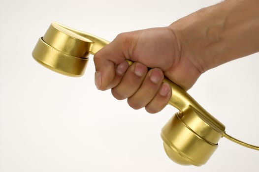 The telephone of gold colour in a hand on a white background.