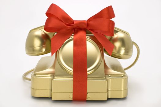 The telephone of gold colour with a red tape on a white background.