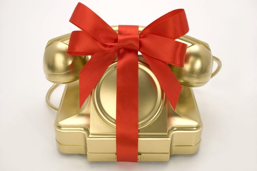 The telephone of gold colour with a red tape on a white background.