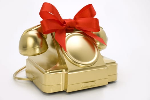 The telephone of gold colour with a red tape on a white background.