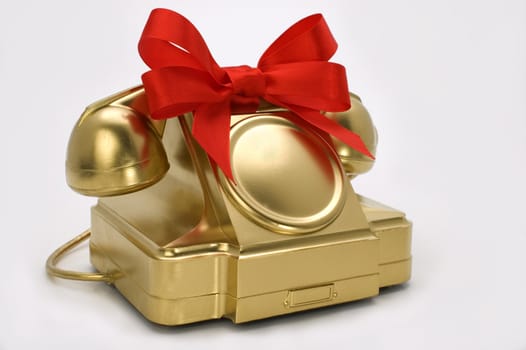 The telephone of gold colour with a red tape on a white background.