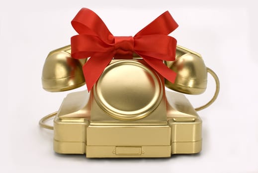 The telephone of gold colour with a red tape on a white background.