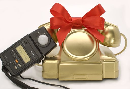 The telephone of gold colour with a red tape on a white background.