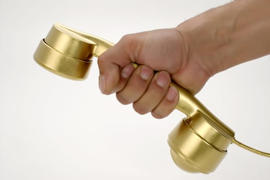 The telephone of gold colour in a hand on a white background.
