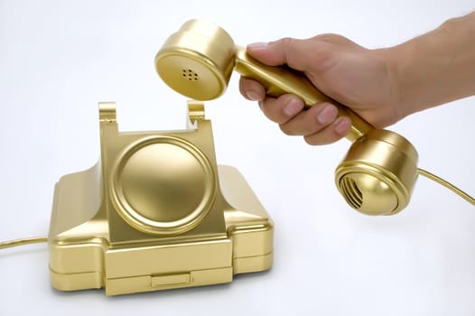 The telephone of gold colour in a hand on a white background.