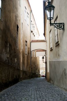 A dark moody image of a small skinny street in the old town area of Prague, Czech Republic.